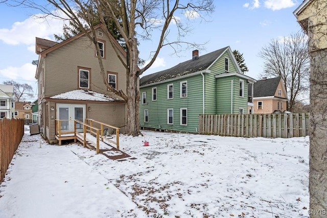 snow covered house featuring fence