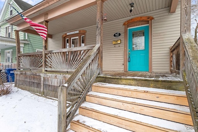 snow covered property entrance with a porch