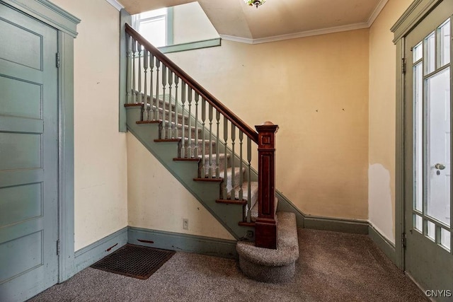 stairway with ornamental molding, carpet, and baseboards