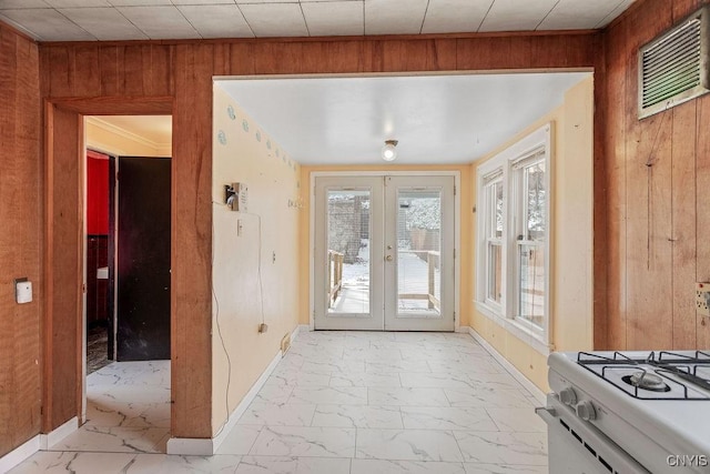 entryway with marble finish floor, baseboards, wooden walls, and french doors