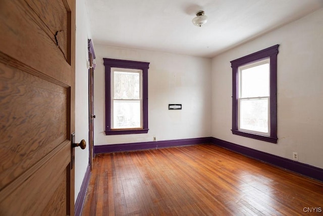 unfurnished room with a healthy amount of sunlight, hardwood / wood-style flooring, and baseboards