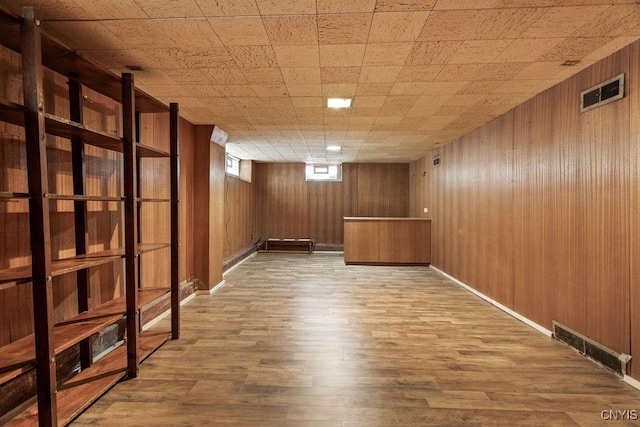 unfurnished room featuring visible vents, wooden walls, and wood finished floors