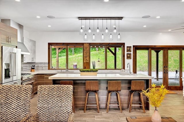 kitchen featuring light countertops, wall chimney exhaust hood, a sink, and high quality appliances