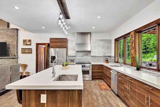 kitchen with a sink, light countertops, appliances with stainless steel finishes, decorative backsplash, and wall chimney exhaust hood