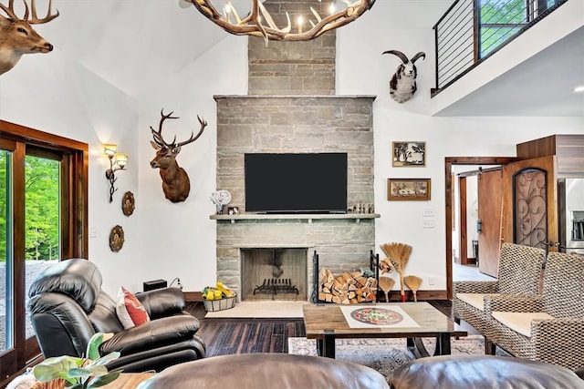 living area with high vaulted ceiling, a fireplace, and a notable chandelier