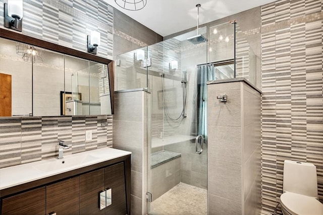 full bath with toilet, a shower stall, tile walls, and vanity