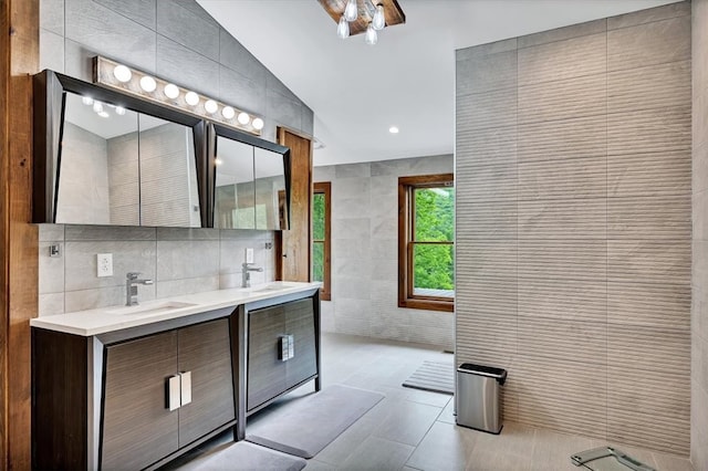 bathroom with tile patterned flooring, a sink, tile walls, and double vanity