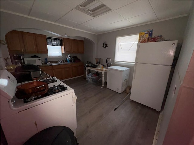 kitchen featuring arched walkways, white appliances, light wood-type flooring, and plenty of natural light