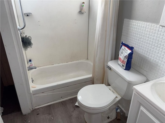 full bath with shower / tub combo with curtain, tile walls, toilet, vanity, and wood finished floors