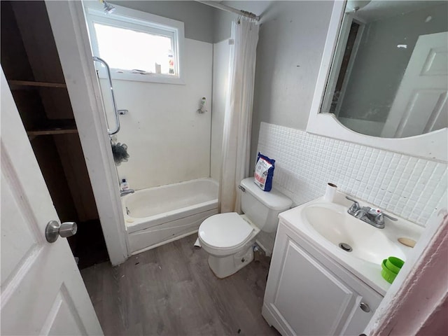 bathroom with toilet, wood finished floors, shower / bath combination with curtain, vanity, and tile walls