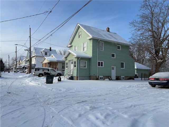 view of snowy exterior featuring entry steps and a chimney