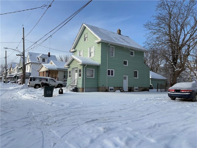 view of snow covered exterior featuring entry steps and a chimney