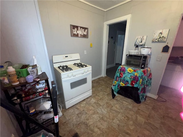 kitchen featuring white range with gas stovetop, a toaster, baseboards, and tile patterned floors