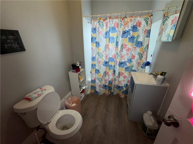 bathroom with toilet, curtained shower, a sink, and wood finished floors