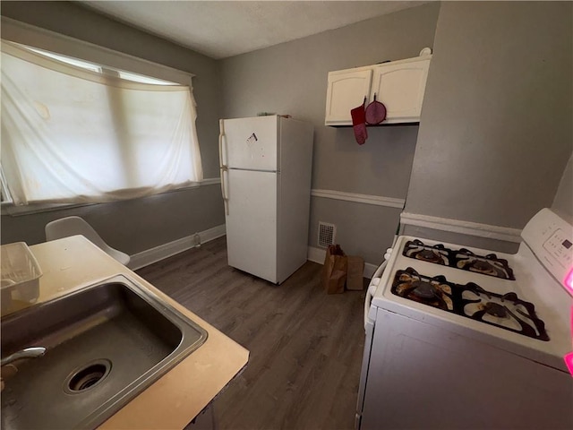 kitchen featuring white appliances, visible vents, dark wood-style floors, white cabinetry, and a sink