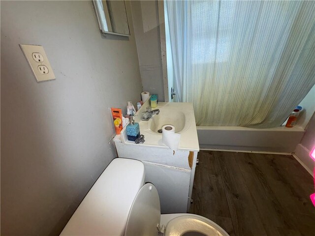 full bathroom with toilet, shower / bath combo with shower curtain, wood finished floors, and vanity