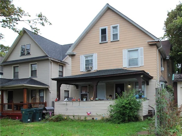 rear view of house with covered porch, a yard, and cooling unit