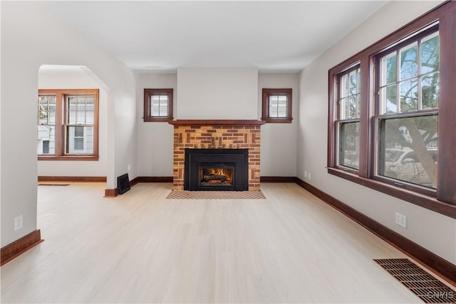 living room featuring baseboards, a fireplace, visible vents, and wood finished floors