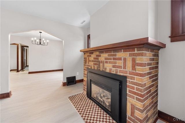 room details with arched walkways, a fireplace, wood finished floors, baseboards, and an inviting chandelier