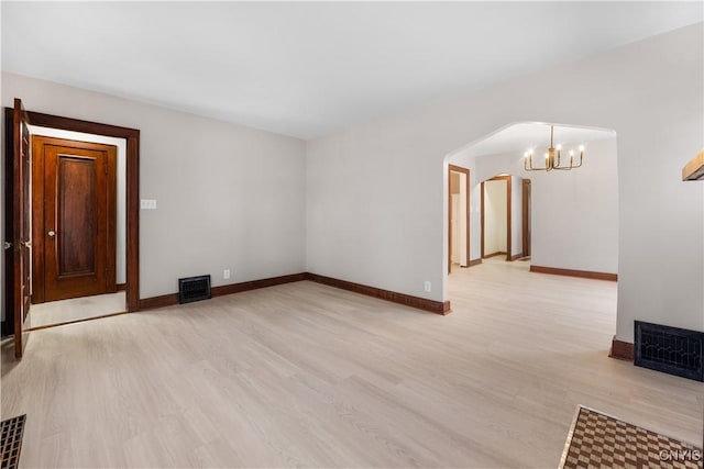 unfurnished living room with arched walkways, light wood-style flooring, visible vents, and baseboards