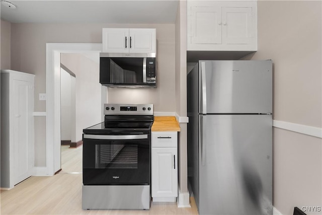 kitchen with baseboards, white cabinets, appliances with stainless steel finishes, light wood-style floors, and wooden counters