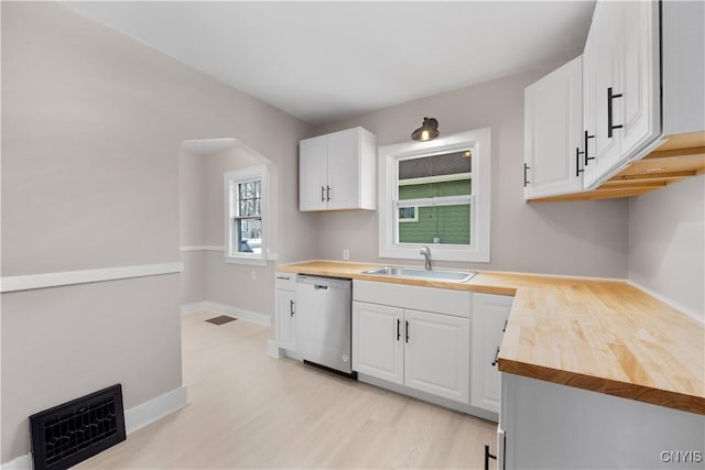 kitchen with butcher block counters, white cabinetry, a sink, and stainless steel dishwasher