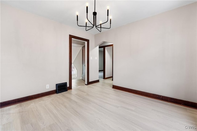 unfurnished dining area with baseboards, arched walkways, light wood-style flooring, and a notable chandelier