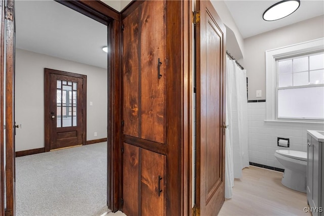 corridor with light carpet, tile walls, and a wealth of natural light