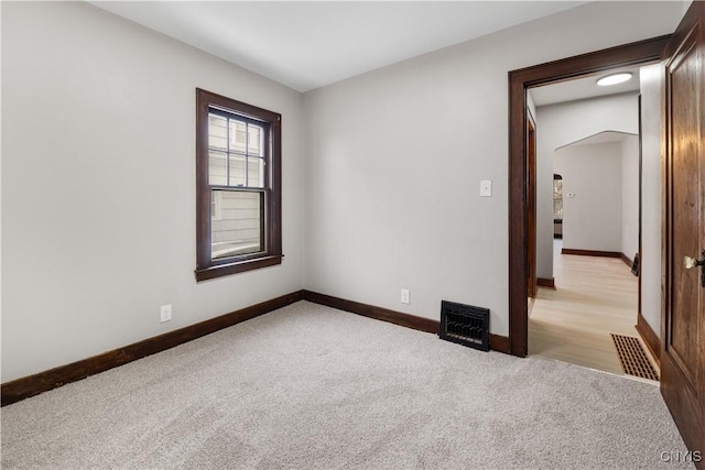 spare room featuring light carpet, visible vents, and baseboards