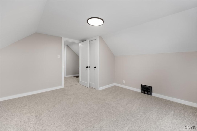 additional living space with lofted ceiling, light carpet, visible vents, and baseboards