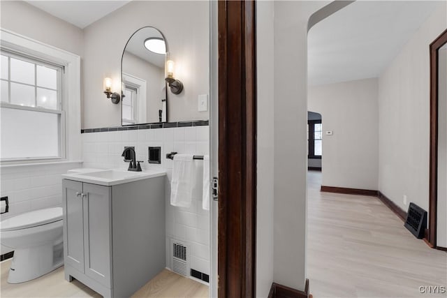 bathroom featuring vanity, tile walls, toilet, and wood finished floors