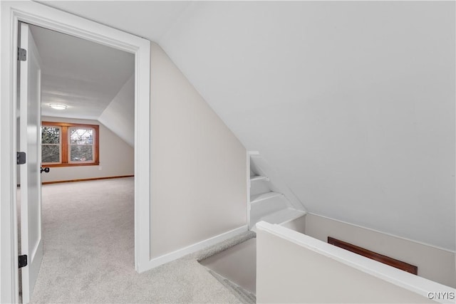 interior space featuring carpet, baseboards, and vaulted ceiling