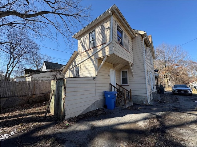 back of property featuring entry steps and fence