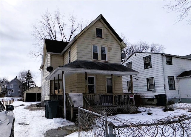 view of front of property with a detached garage, a porch, and an outbuilding