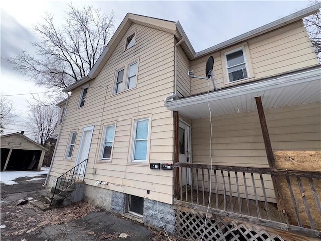 view of property exterior featuring entry steps, covered porch, and a detached garage