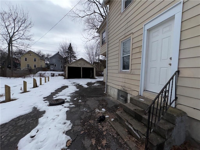 snowy yard with entry steps, a garage, and an outdoor structure