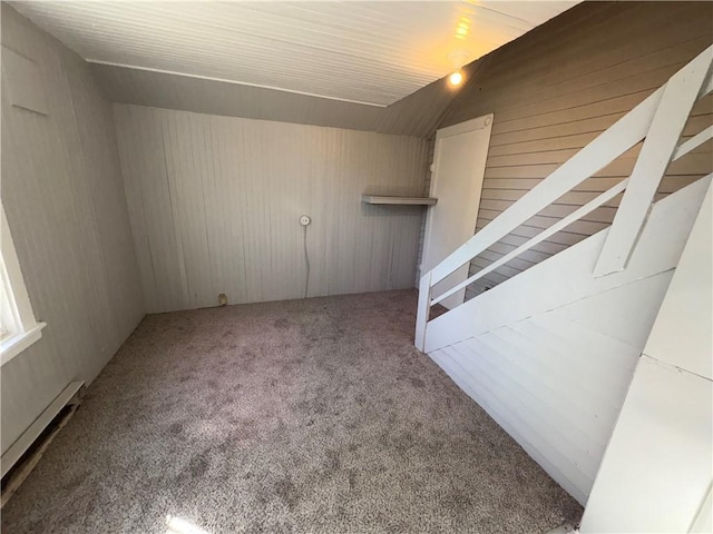 interior space with a baseboard heating unit, carpet flooring, and wooden walls