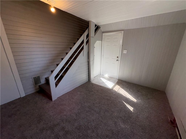 interior space featuring carpet flooring, visible vents, and wooden walls