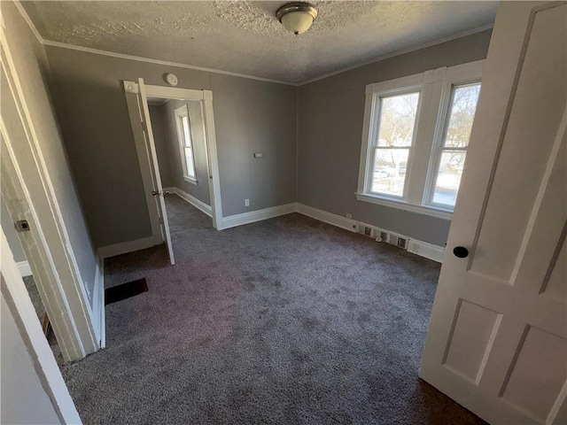 unfurnished bedroom with a textured ceiling, dark carpet, and crown molding