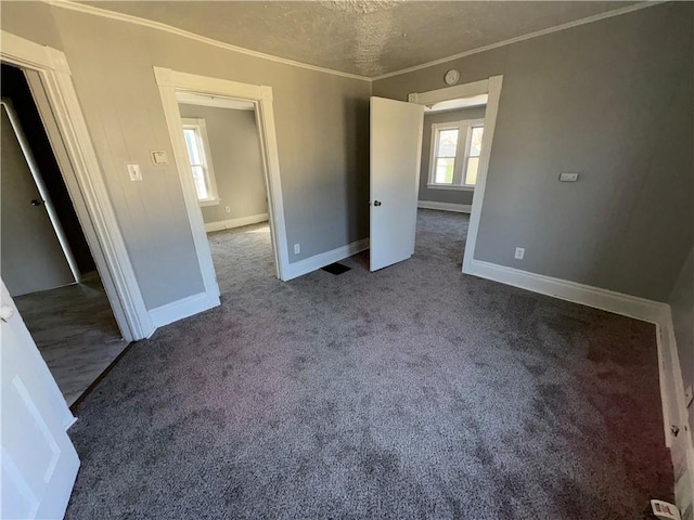 unfurnished bedroom featuring baseboards, a textured ceiling, ornamental molding, and carpet flooring