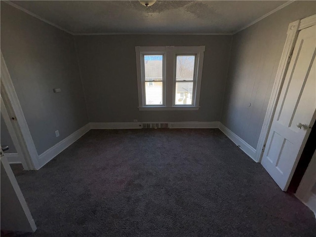 unfurnished bedroom with baseboards, visible vents, dark colored carpet, a textured ceiling, and crown molding