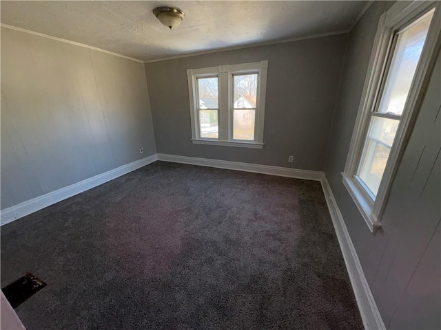 empty room with baseboards, a textured ceiling, dark carpet, and crown molding