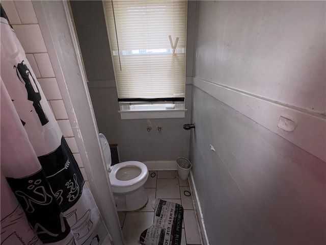 bathroom featuring baseboards, curtained shower, toilet, and tile patterned floors