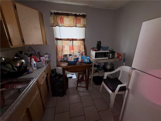 kitchen featuring light tile patterned floors, light countertops, a sink, and freestanding refrigerator