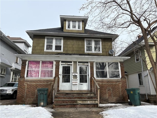 american foursquare style home featuring brick siding and entry steps