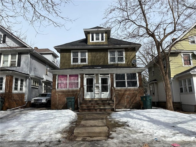 american foursquare style home featuring brick siding and entry steps