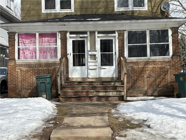 snow covered property entrance with brick siding