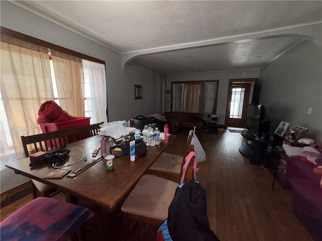 dining room with arched walkways and wood finished floors