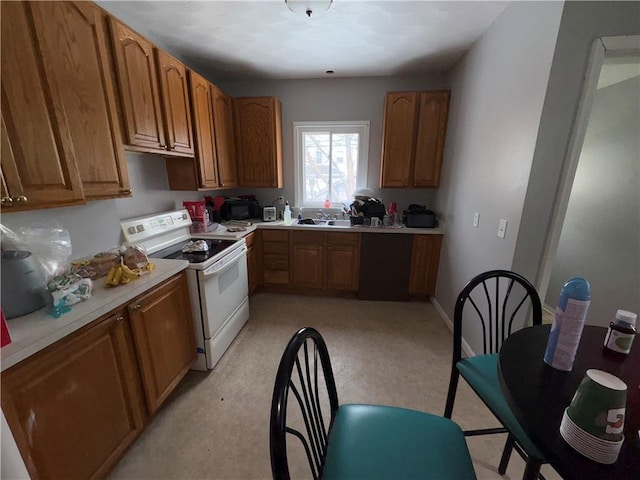 kitchen featuring baseboards, light countertops, brown cabinets, white electric range, and a sink