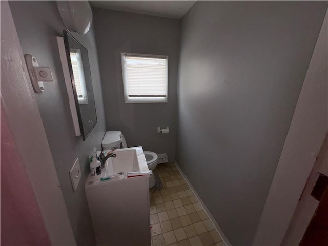 half bathroom featuring tile patterned floors, toilet, vanity, and baseboards